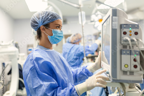 Anesthesiologist keeping track of vital functions of the body during cardiac surgery. Surgeon looking at medical monitor during surgery. Doctor checking monitor for patient health status.