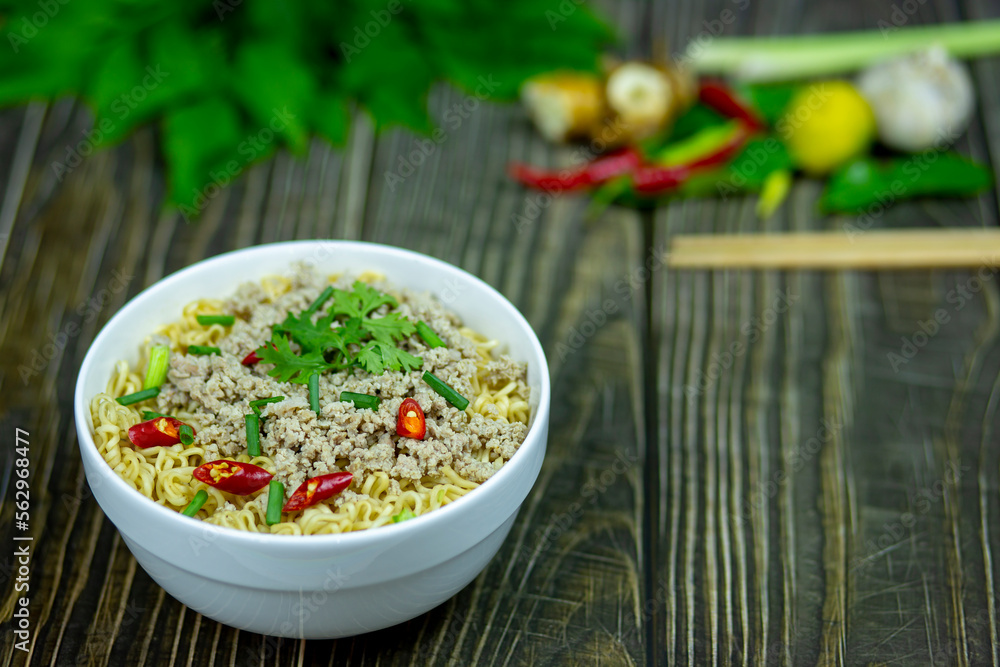 Noodles with minced pork on top herb hot spicy flavor in bowl serve on a dark dining table ready to eating with family is dinner. Noodles with minced pork on top herb hot spicy flavor in bowl serve on a dark dining table ready to eating with family is dinner.