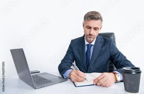 mature manager writing at the table in business office