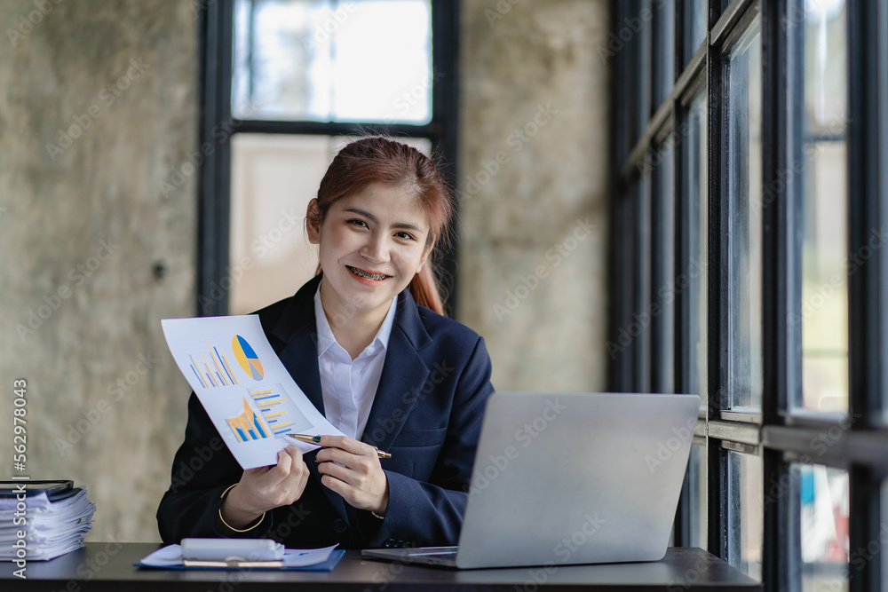 Asian businesswoman working in office with documents and laptop Worker documents calculating financial indicators smiling and happy success Asian businesswoman working in office with documents and laptop Worker documents calculating financial indicators smiling and happy success
