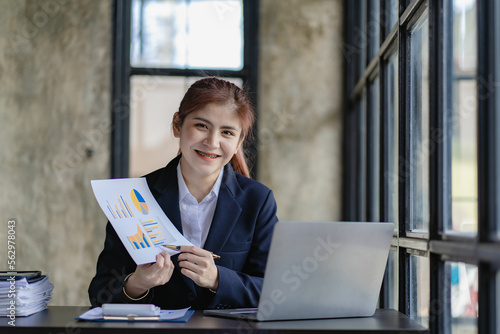 Asian businesswoman working in office with documents and laptop Worker documents calculating financial indicators smiling and happy success
