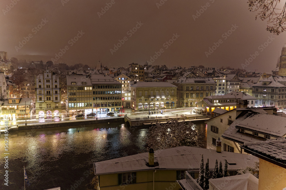 Aerial view of the old town of City of Zürich on a late autumn night with snowfall and Great Minster church in the background. Photo taken December 10th, 2022, Zurich, Switzerland.