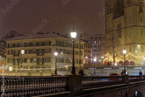 Old town of City of Zürich on a late autumn night with snowfall and Minster Bridge with Great Minster church in the background. Photo taken December 10th, 2022, Zurich, Switzerland.