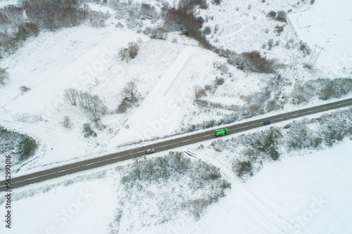 drone aerial view of three vehicles in a road in a snowy landscape, winter transportation concept