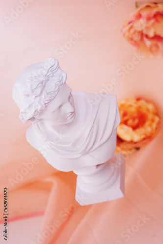 Statue of Apollo hovering over flowers on a beige background. modern art concept