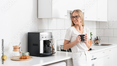 happy woman standing with mug and drink coffee at home kitchen