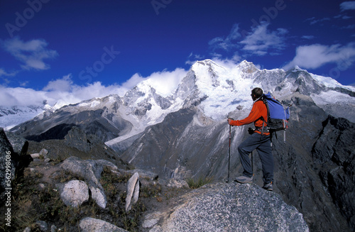 Man standing on a peak looking out at snow covered mountains in Cordillera Blanca, Peru. photo