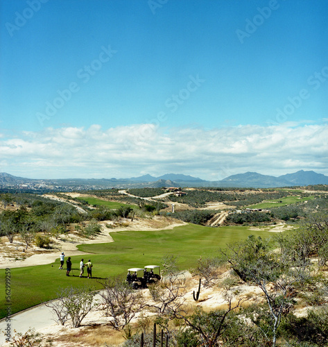 A foursome tees off on a golf course in the desert. photo