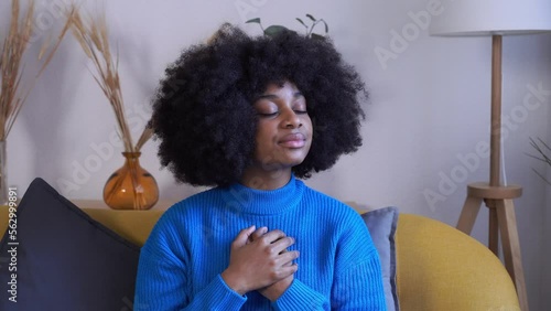 Black woman with curly hair meditating at home