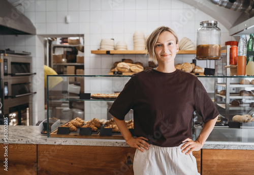 Photography Portrait of smiling young woman entrepreneur standing at the counter of her bakery and coffee shop