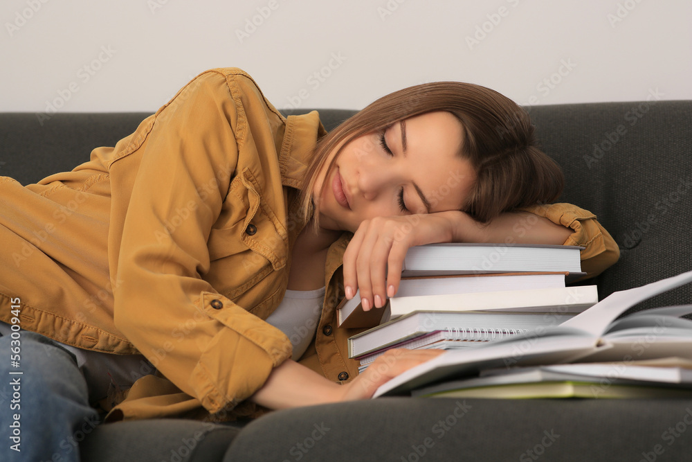 Young tired woman sleeping near books on couch indoors Young tired woman sleeping near books on couch indoors