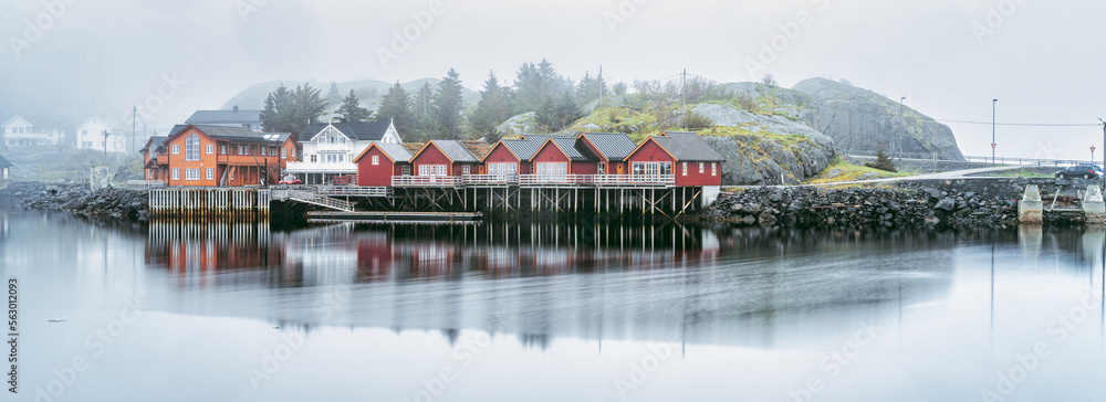 Reine in Lofoten, norway, typical red colored houses surrounded by water during a cloudy day with spring mist