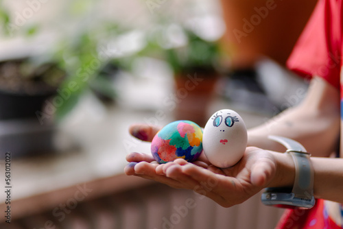 Funny painted eggs in the hands of a child. Easter celebration is a Christian tradition. Entertainment with children. Drawing on the egg in the form of a funny face muzzle