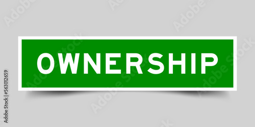 Green color square label sticker with word ownership on gray background