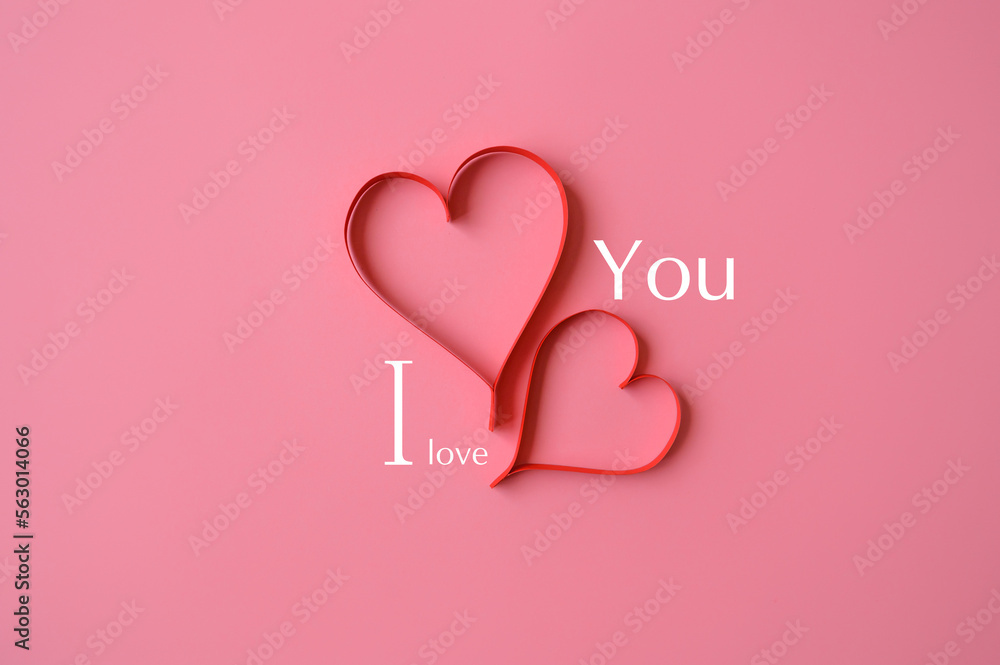 Two red hearts made of paper on a pink background with the text I love you. Background for a valentine's postcard. valentine day. Love concept. Declaration of love