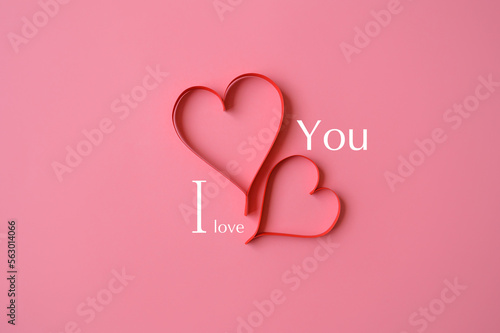 Foto Two red hearts made of paper on a pink background with the text I love you