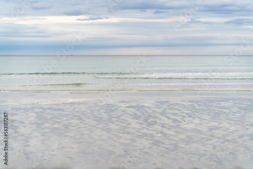 Waves coming onto the beach at Rambergstranda beach in Lofoten  Norway  during spring on a clear day with clouds