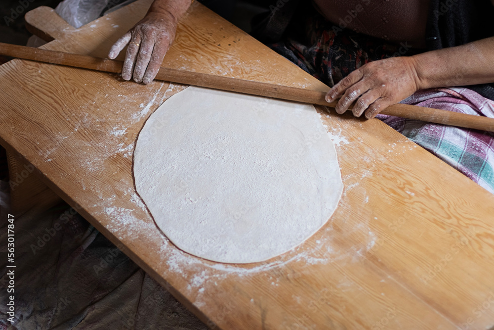 Rolling dough using rolling pin. Women's hands in flour roll out the dough with a rolling pin on the table. Rolling dough using rolling pin. Women's hands in flour roll out the dough with a rolling pin on the table.