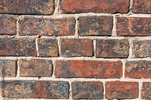 Brickwork on the wall of an old house built in the 19th century. The background is made of old brick. Full-bodied clay brick. Material for building construction.