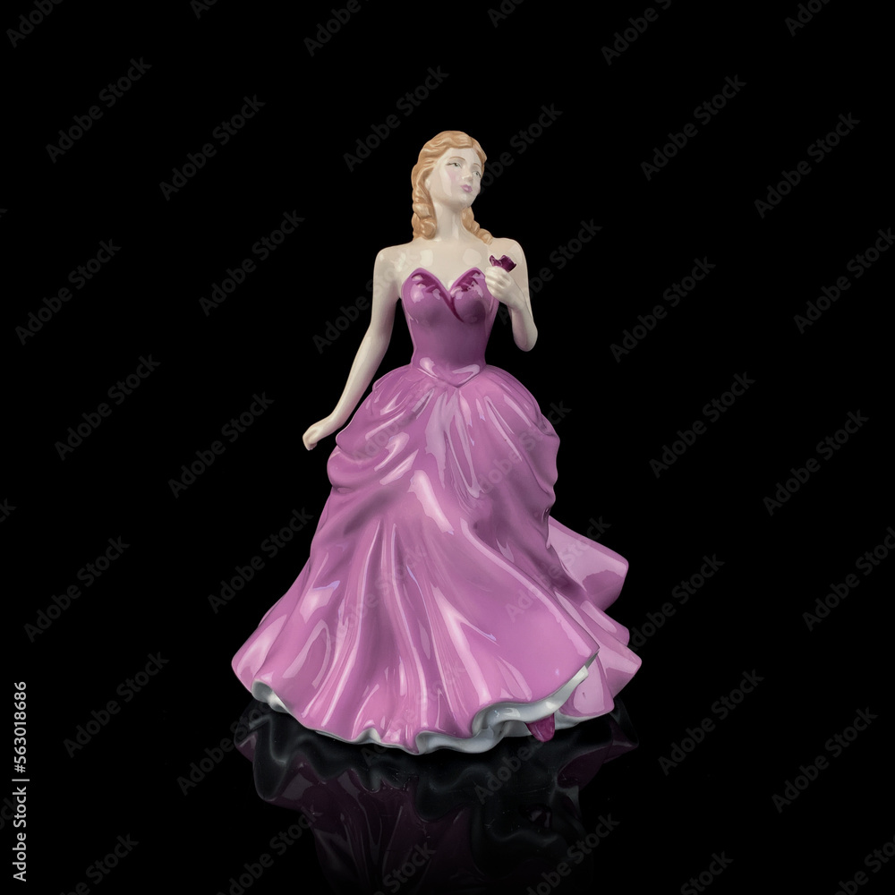 Vintage porcelain figurine of a woman in a long  pink dress on a black background.