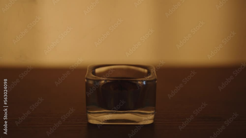 A red candle on a wooden table. Blowing out, against a background of flickering light, close-up A red candle on a wooden table. Blowing out, against a background of flickering light, close-up