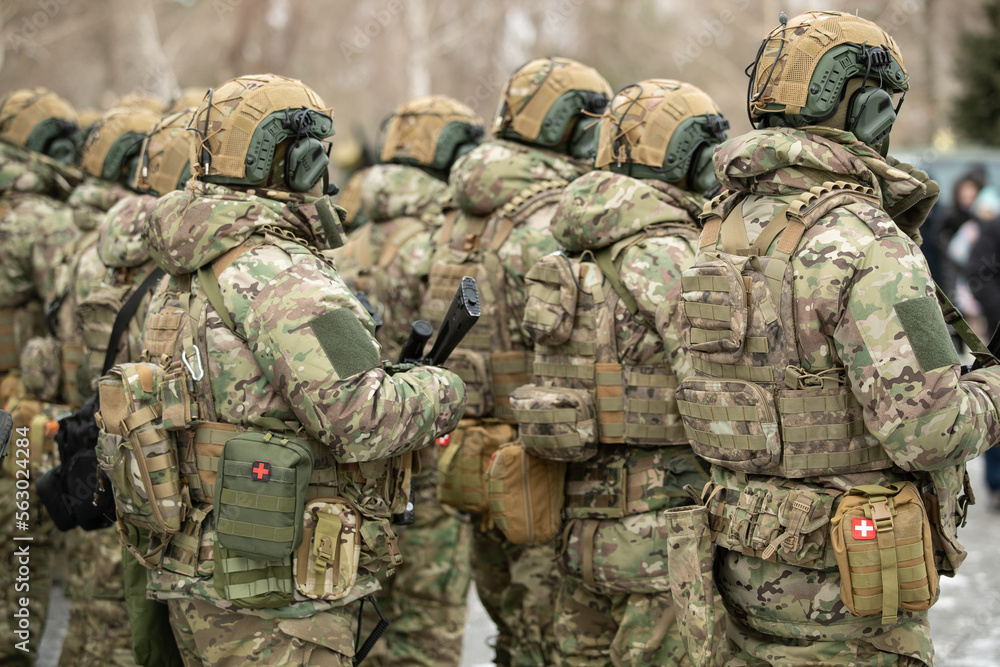 Fototapeta premium Army soldier with a machine gun in his hand. Soldier, commando standing, ready for combat training. Military fashion. Army parade - a march of soldiers in uniform.