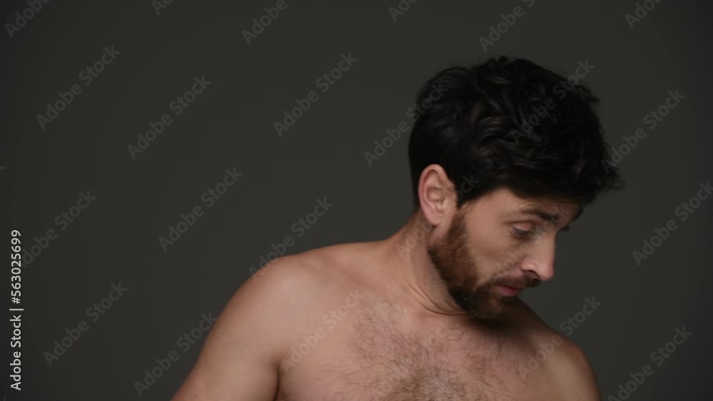 Shirtless and disheveled man using hairspray and smiling isolated on dark grey Shirtless and disheveled man using hairspray and smiling isolated on dark grey