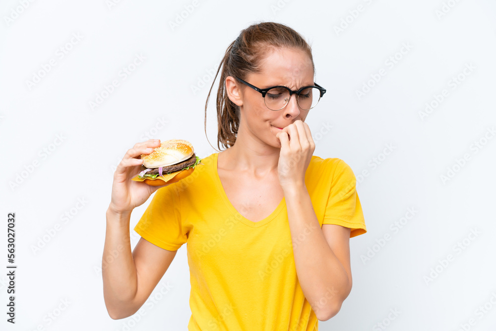 Young caucasian woman holding a burger isolated on white background having doubts Young caucasian woman holding a burger isolated on white background having doubts