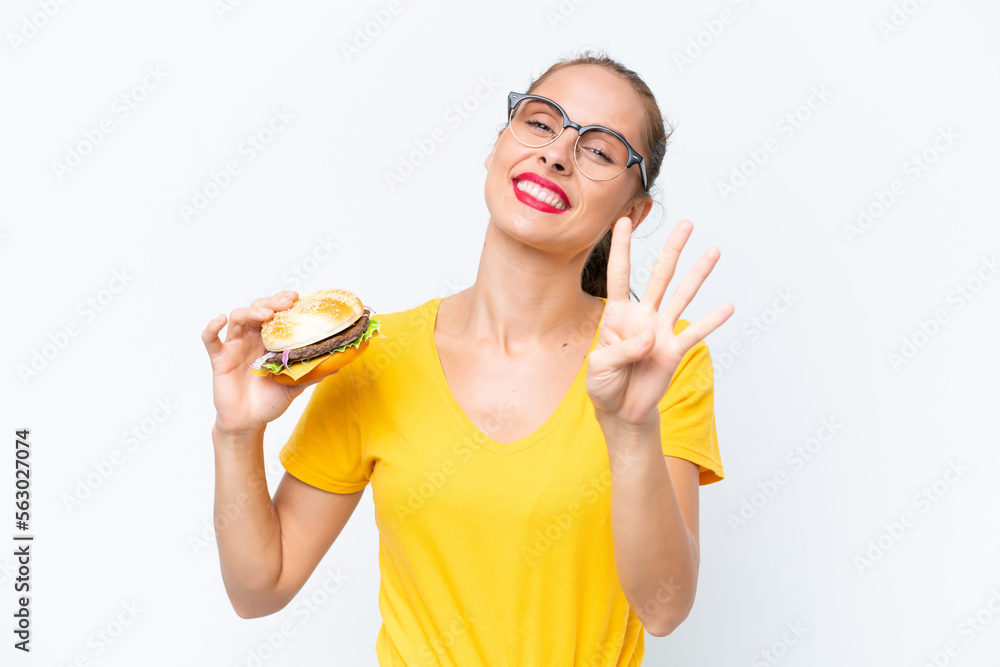 Young caucasian woman holding a burger isolated on white background happy and counting four with fingers Young caucasian woman holding a burger isolated on white background happy and counting four with fingers