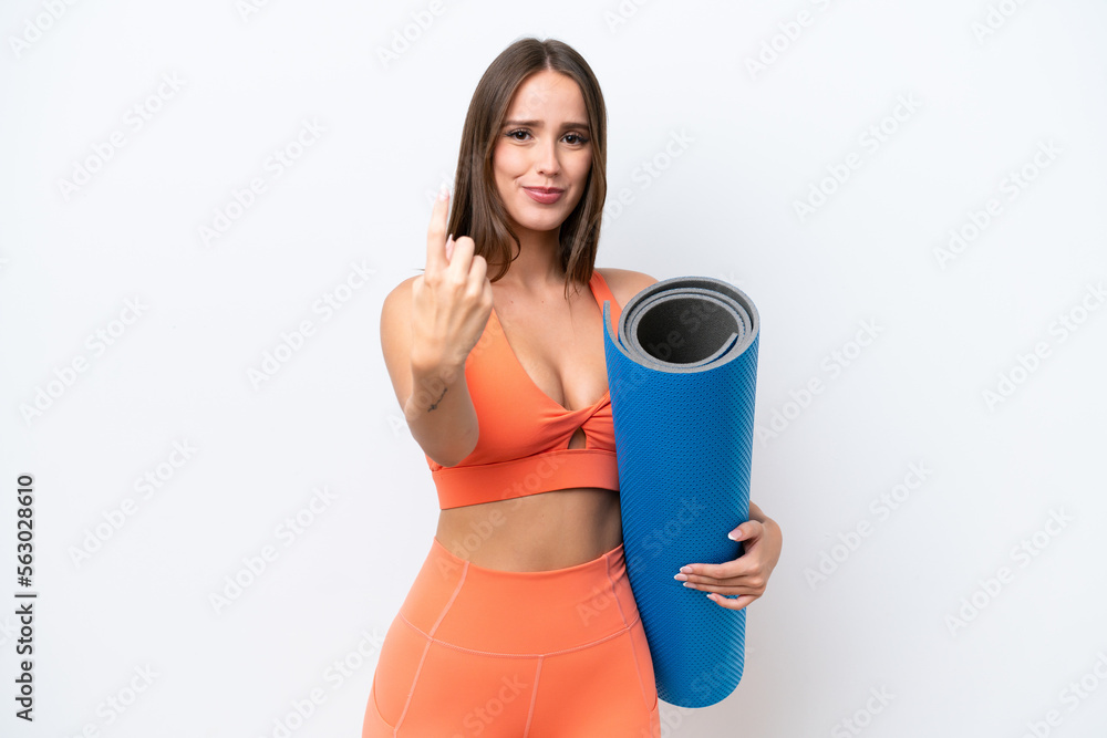 Young beautiful sport woman going to yoga classes while holding a mat isolated on white background doing coming gesture Young beautiful sport woman going to yoga classes while holding a mat isolated on white background doing coming gesture
