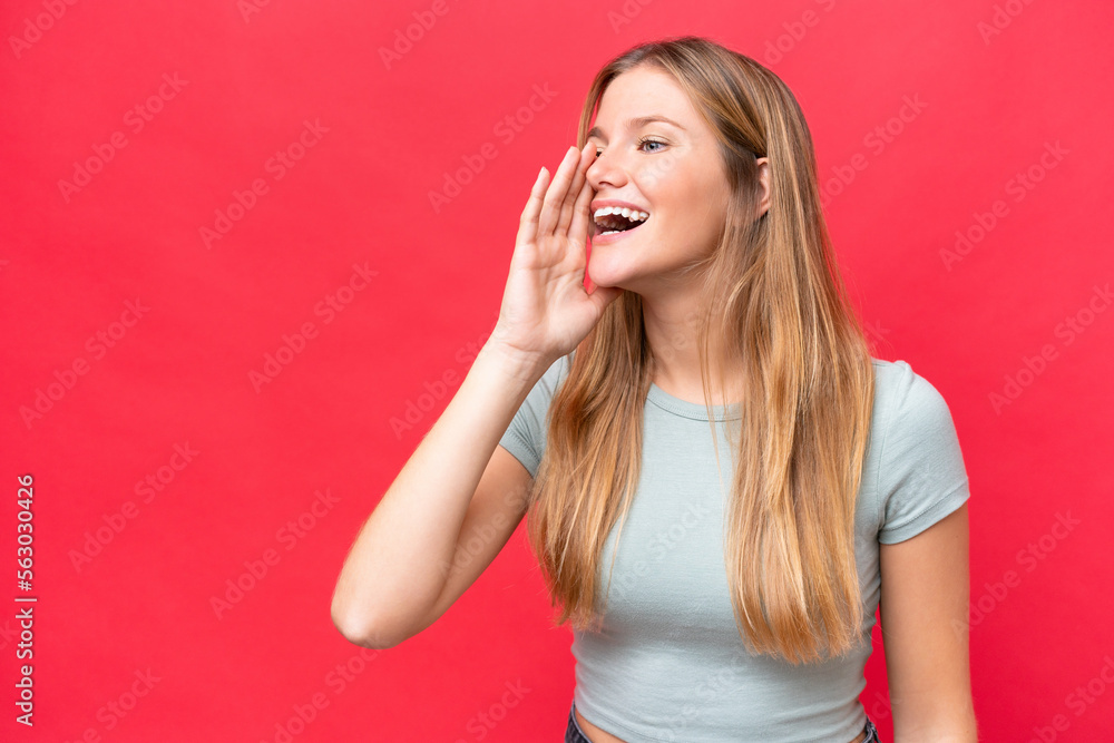 Young beautiful woman isolated on red background shouting with mouth wide open to the side Young beautiful woman isolated on red background shouting with mouth wide open to the side