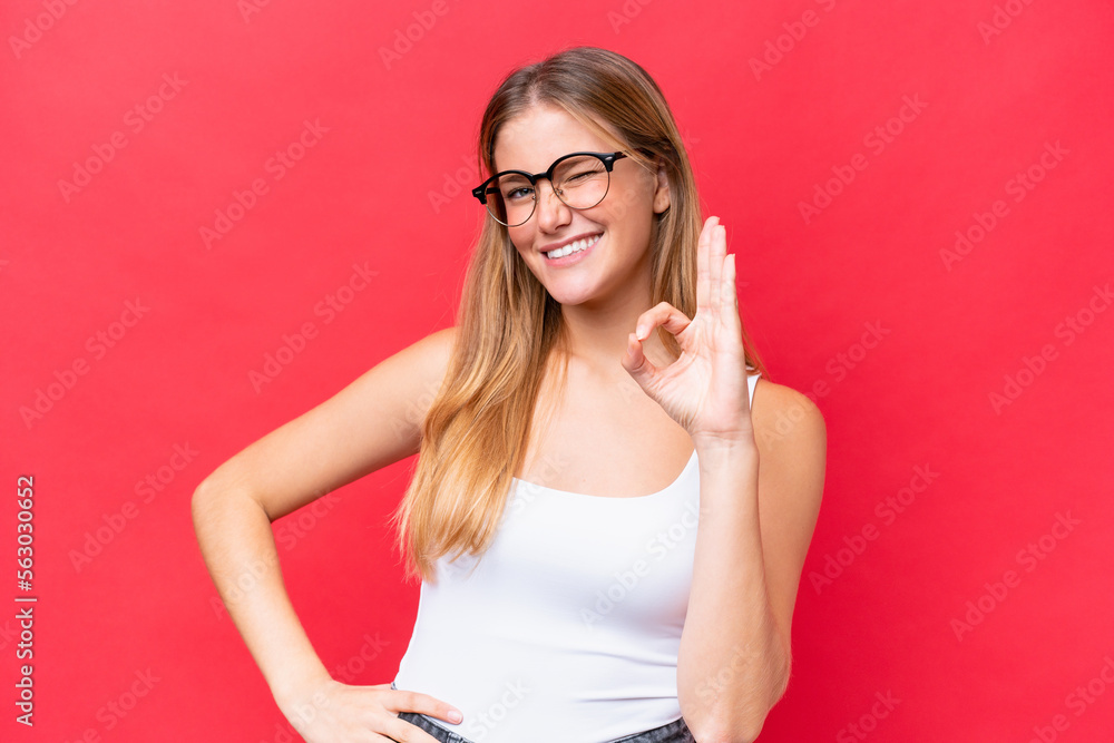 Young beautiful woman isolated on red background showing ok sign with fingers