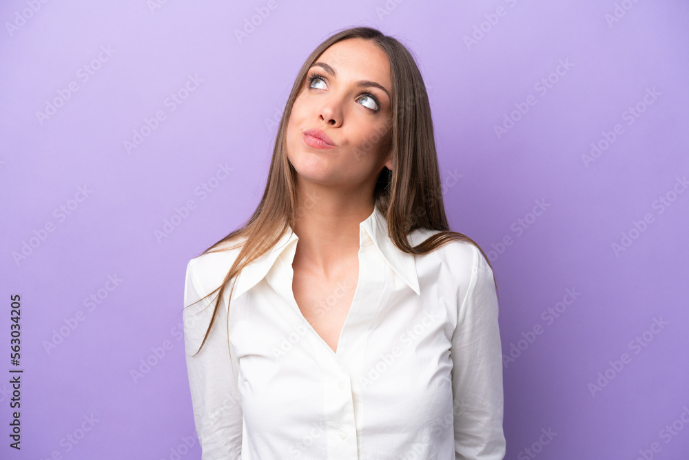 Obraz premium Young caucasian woman isolated on purple background and looking up