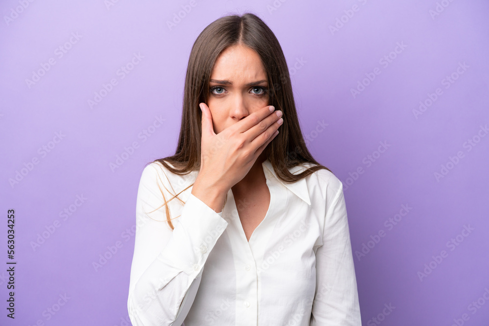 Young caucasian woman isolated on purple background covering mouth with hand Young caucasian woman isolated on purple background covering mouth with hand