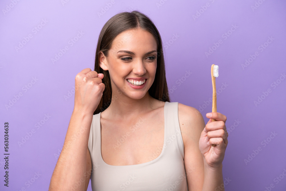 Young caucasian woman brushing teeth isolated on purple background celebrating a victory Young caucasian woman brushing teeth isolated on purple background celebrating a victory