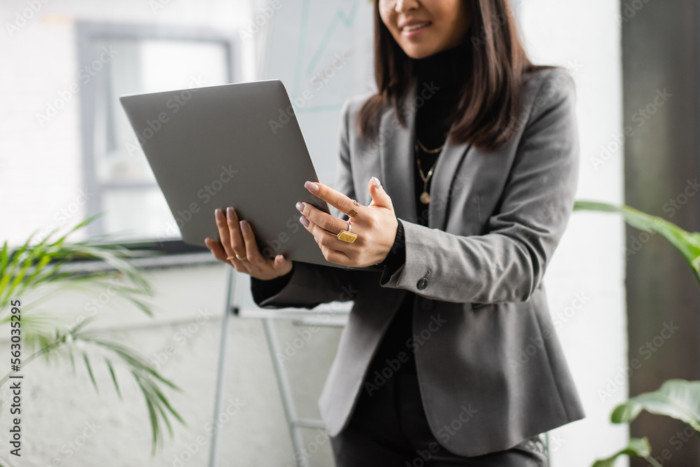 Cropped view of blurred designer holding laptop in studio. Cropped view of blurred designer holding laptop in studio.