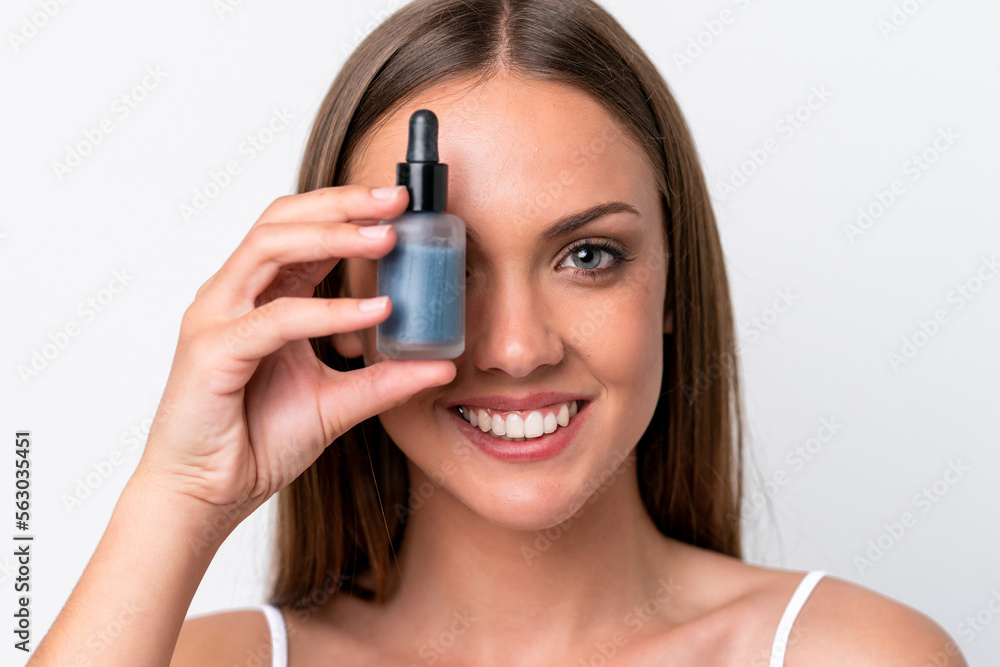 Young caucasian woman isolated on white background holding a serum while smiling. Close up portrait Young caucasian woman isolated on white background holding a serum while smiling. Close up portrait