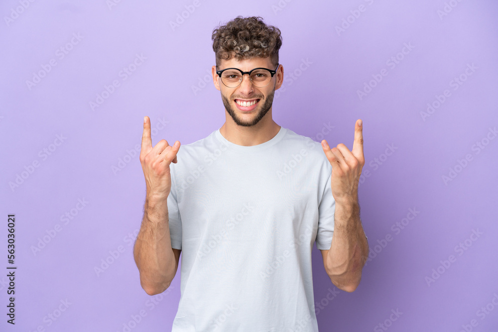 Delivery caucasian man isolated on purple background making horn gesture Delivery caucasian man isolated on purple background making horn gesture