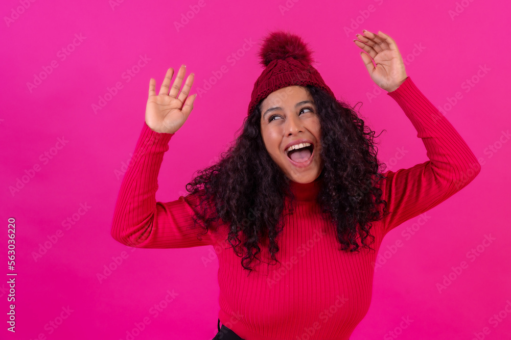 Portrait curly-haired woman in a wool hat on a pink background having fun, studio shot Portrait curly-haired woman in a wool hat on a pink background having fun, studio shot