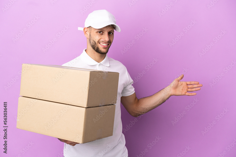 Delivery caucasian man isolated on purple background extending hands to the side for inviting to come Delivery caucasian man isolated on purple background extending hands to the side for inviting to come