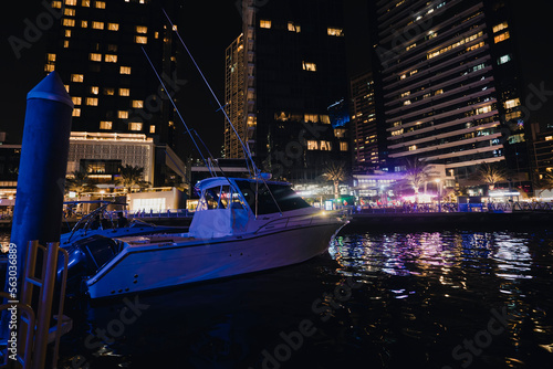 boats in port at Dubai marina at night in bright lights. Marina And Tourist Boat, Sightseeing Boat Sailing On Dubai Marina.