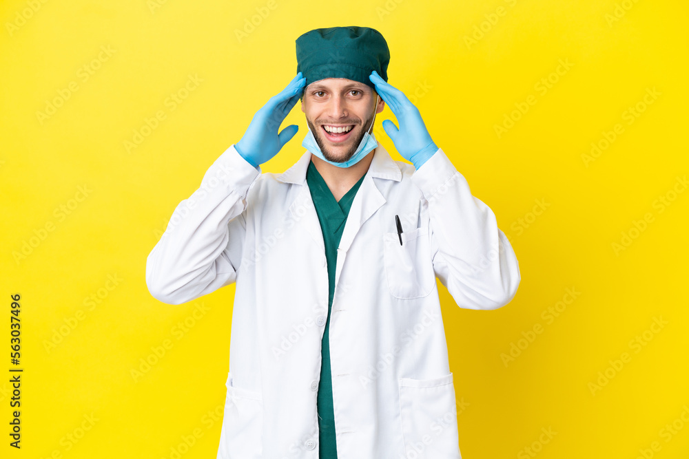 Surgeon blonde man in green uniform isolated on yellow background with surprise expression Surgeon blonde man in green uniform isolated on yellow background with surprise expression