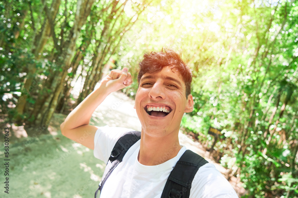 Selfie of Hispanic tourist in the middle of the forest celebrating, happy and excited.