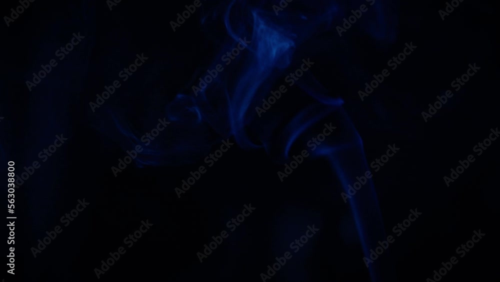 A thin stream of smoke from an extinguished scented candle after meditation in a semi-dark studio with a black background. A thin stream of smoke from an extinguished scented candle after meditation in a semi-dark studio with a black background.