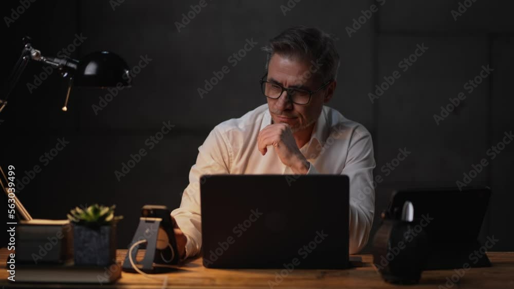 Businessman sitting at desk with laptop computer. Entrepreneur working late in office. Older, middle aged, mid adult, man in his 40s or 50s in business casual. Businessman sitting at desk with laptop computer. Entrepreneur working late in office. Older, middle aged, mid adult, man in his 40s or 50s in business casual.