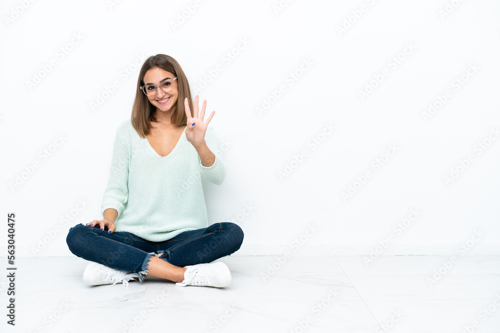Young caucasian woman sitting on the floor isolated on white background happy and counting four with fingers