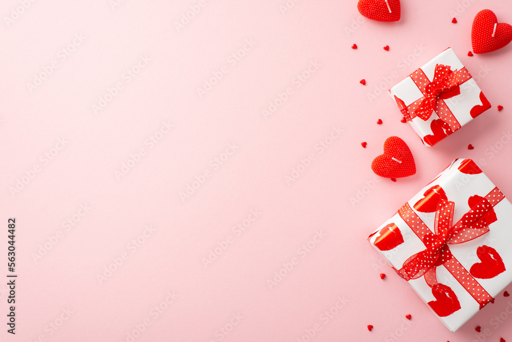 Valentine's Day concept. Top view photo of gift boxes ribbon heart shaped candles and sprinkles on isolated light pink background with empty space Valentine's Day concept. Top view photo of gift boxes ribbon heart shaped candles and sprinkles on isolated light pink background with empty space