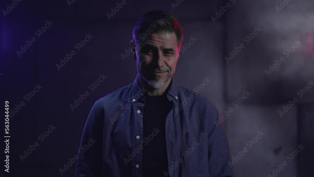 Portrait of happy mature casual man, smiling, standing in front of dark industrial wall. Older, middle aged, mid adult, man in his 40s or 50s in shirt. Portrait of happy mature casual man, smiling, standing in front of dark industrial wall. Older, middle aged, mid adult, man in his 40s or 50s in shirt.
