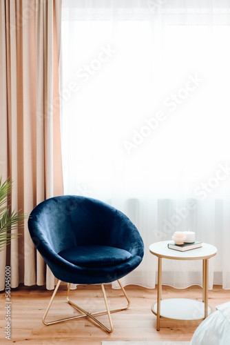 Reading area with comfortable chair and table next to window on modern apartment