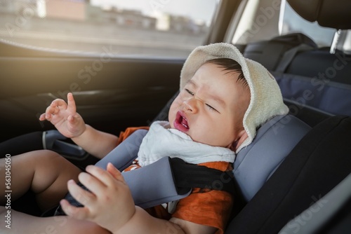 The toddler boy is crying in the car seat while going to school. feel uncomfortable while the car is moving. bad mood, negative emotion. close up.